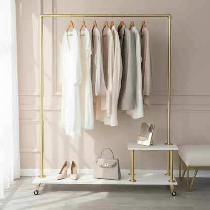Gold clothing rack with clothes, shoes, and handbag on a neutral background