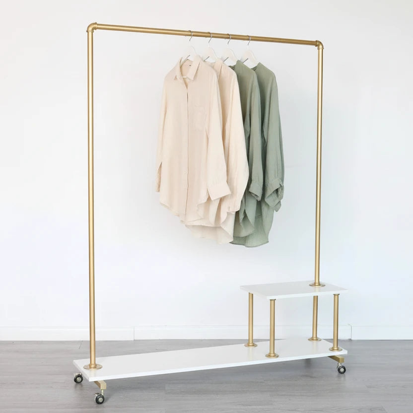 Gold clothing rack with white board in a room with framed pictures on the wall
