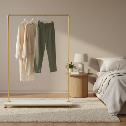 Gold clothing rack with green pants and beige jacket on a white background